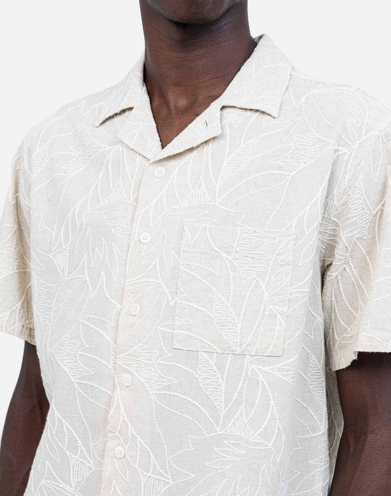 Fine all-over embroideries trace a subtle botanical pattern on this Hawaiian-cut short-sleeved shirt. A summery, bright, and relaxed silhouette, carried by a soft ecru shade that is easy to integrate into any summer wardrobe. Crafted from a lightweight, textured fabric, the Aloha Welli shirt combines comfort and structure.