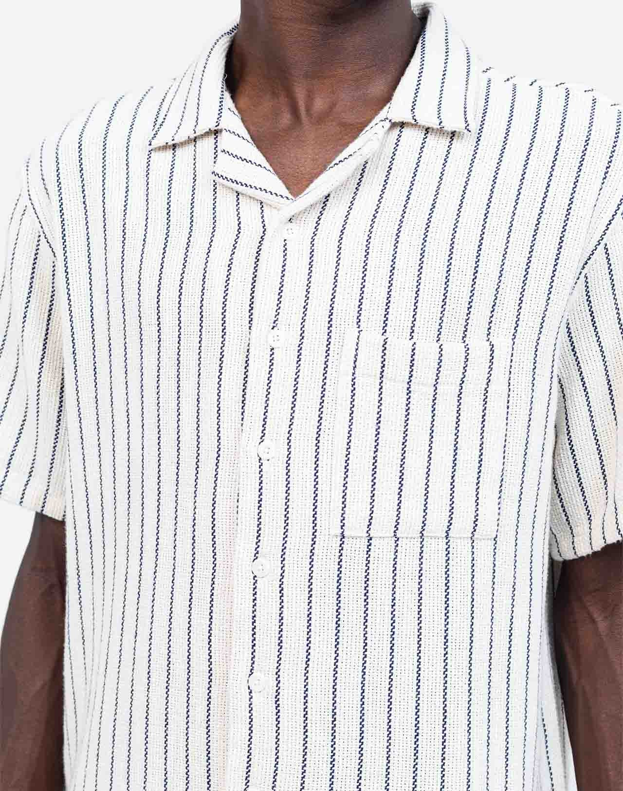 Fine vertical stripes bring a sober and summery elegance to this Hawaiian-cut short-sleeved shirt. A fluid and relaxed silhouette, ideal for sunny days and summer evenings alike. Crafted from 65% cotton and 35% recycled cotton (205g) and featuring corozo buttons, the Aloha Rivas shirt combines the perfect mix of comfort and structure.