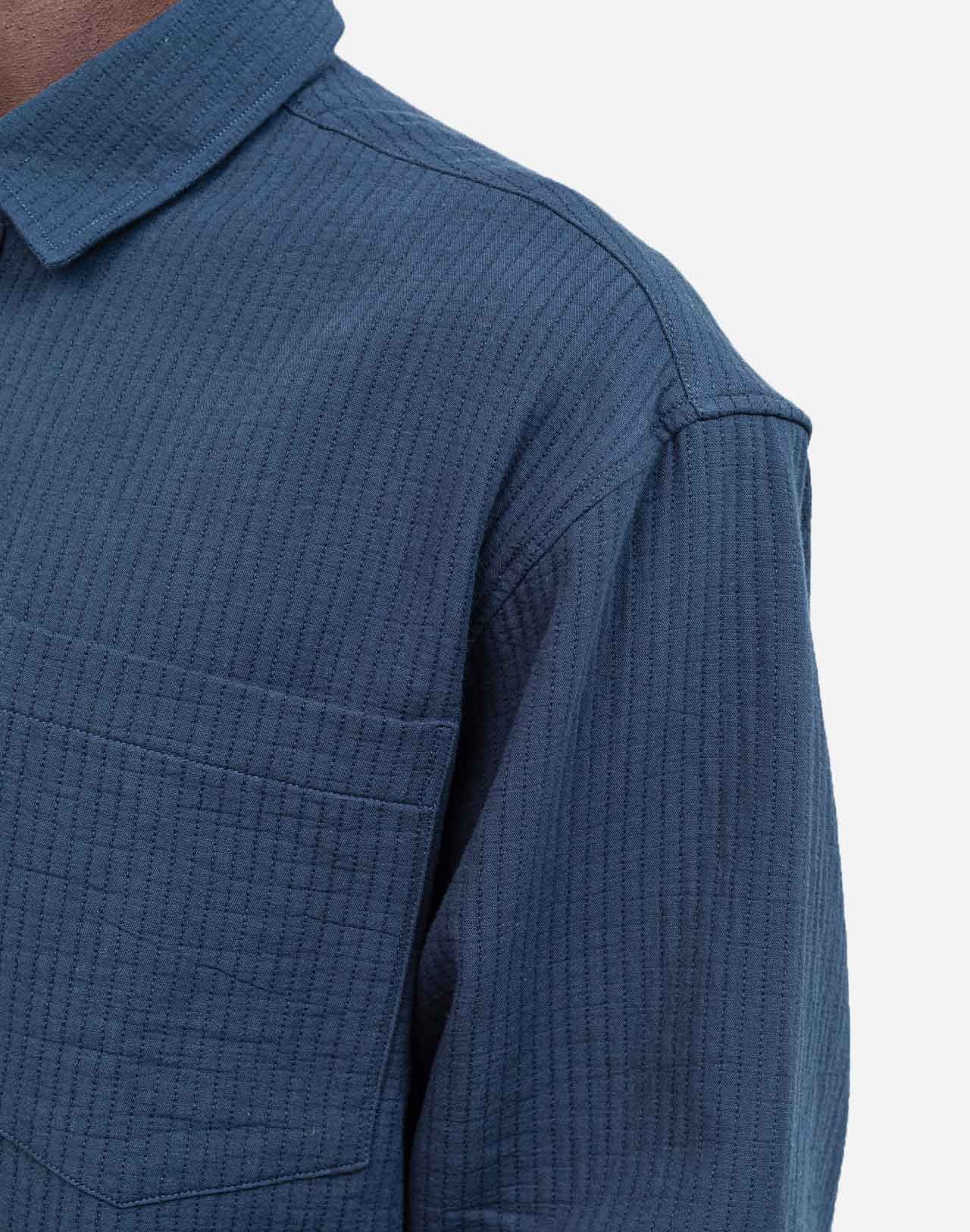 A straight-cut shirt with a curved hem, crafted from a soft and comfortable cotton gauze woven in France, textured with rows of topstitching. A timeless fit that can be worn for any occasion.