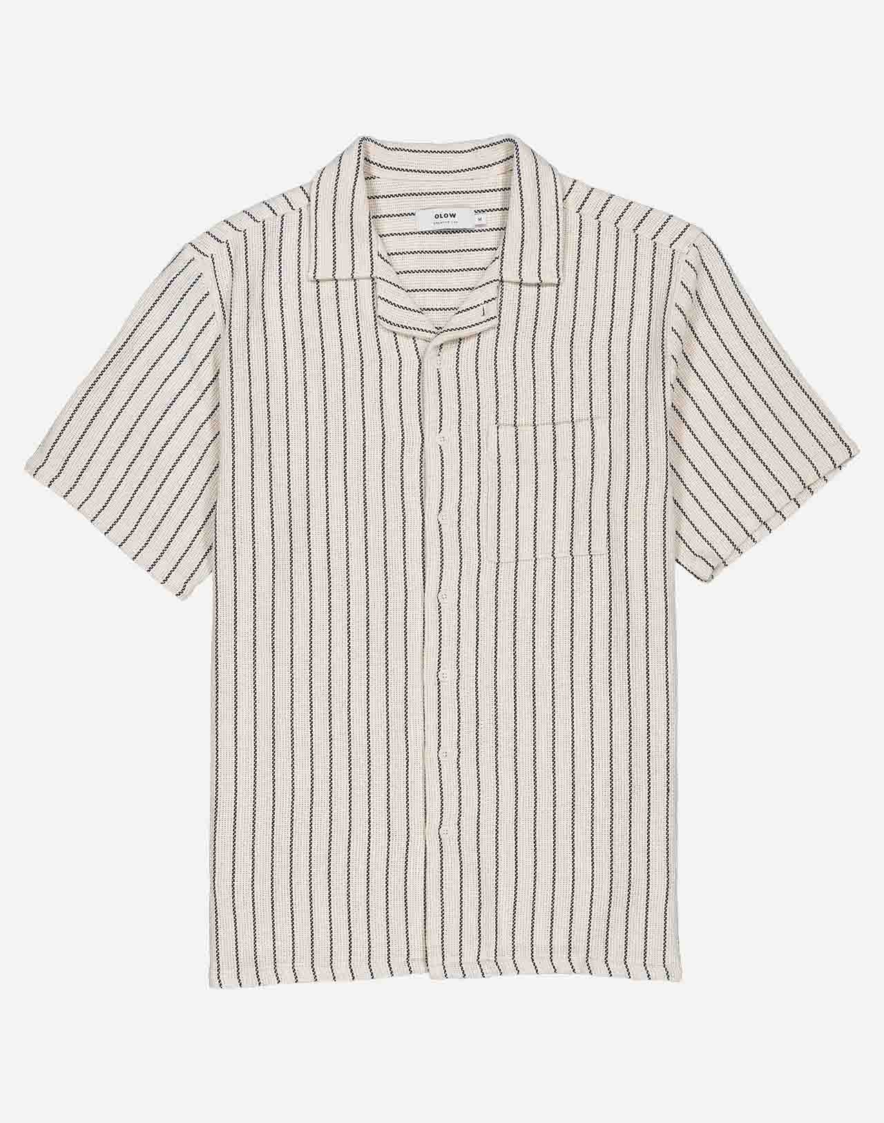 Fine vertical stripes bring a sober and summery elegance to this Hawaiian-cut short-sleeved shirt. A fluid and relaxed silhouette, ideal for sunny days and summer evenings alike. Crafted from 65% cotton and 35% recycled cotton (205g) and featuring corozo buttons, the Aloha Rivas shirt combines the perfect mix of comfort and structure.
