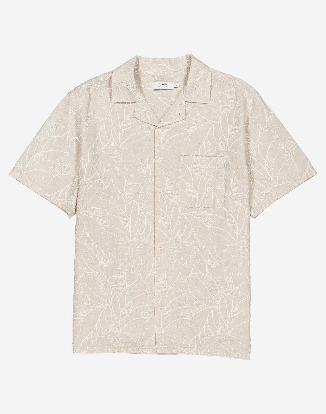 Fine all-over embroideries trace a subtle botanical pattern on this Hawaiian-cut short-sleeved shirt. A summery, bright, and relaxed silhouette, carried by a soft ecru shade that is easy to integrate into any summer wardrobe. Crafted from a lightweight, textured fabric, the Aloha Welli shirt combines comfort and structure.