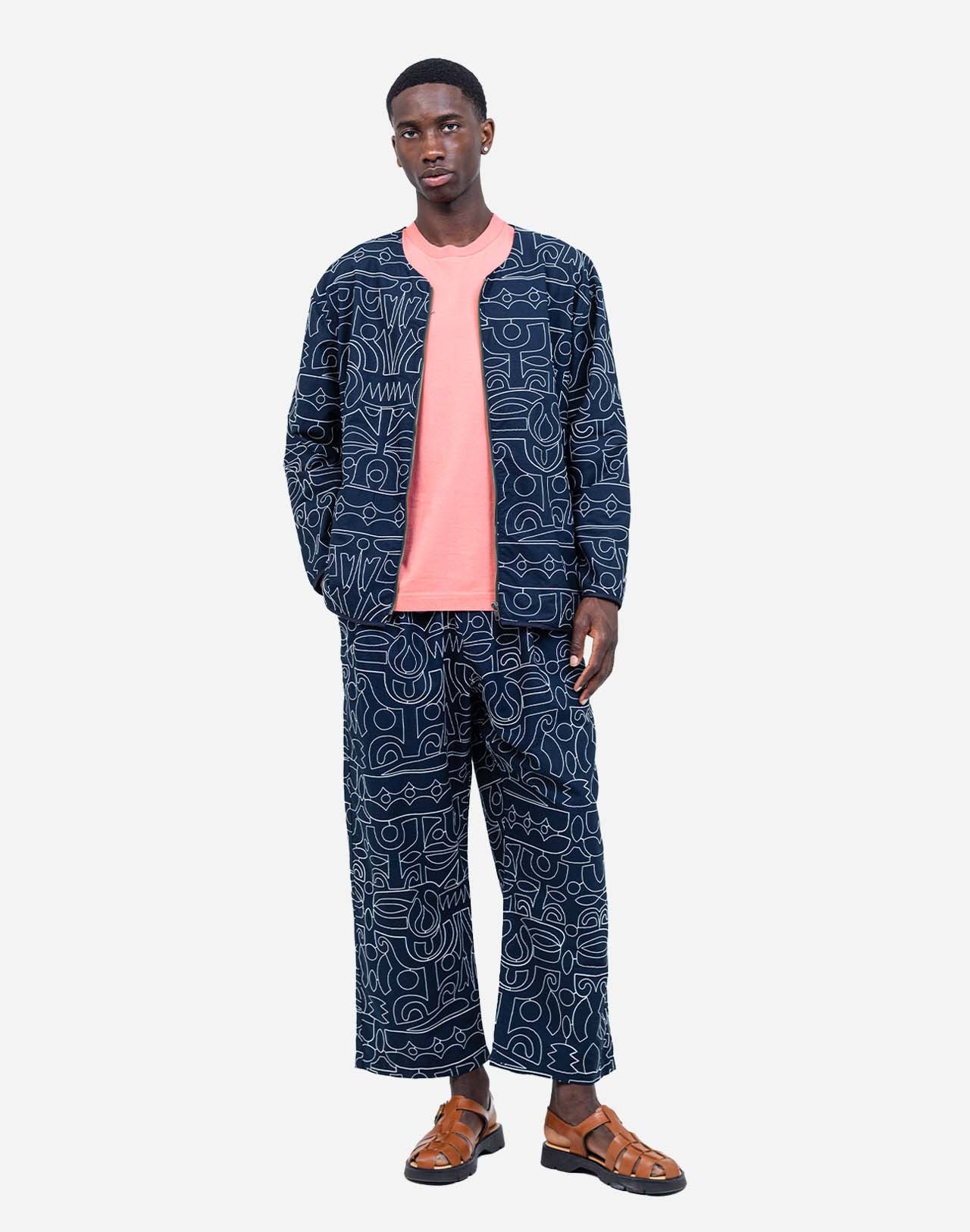 Artist Jeykill’s unique line work is embroidered in an all-over pattern on this organic cotton and recycled polyester zip-up jacket. The combination of dark navy and ecru embroidery makes this garment easy to pair with both vibrant and classic colors, whether worn with jeans or as a total look with the matching trousers. Assuredly a standout piece of the collection.