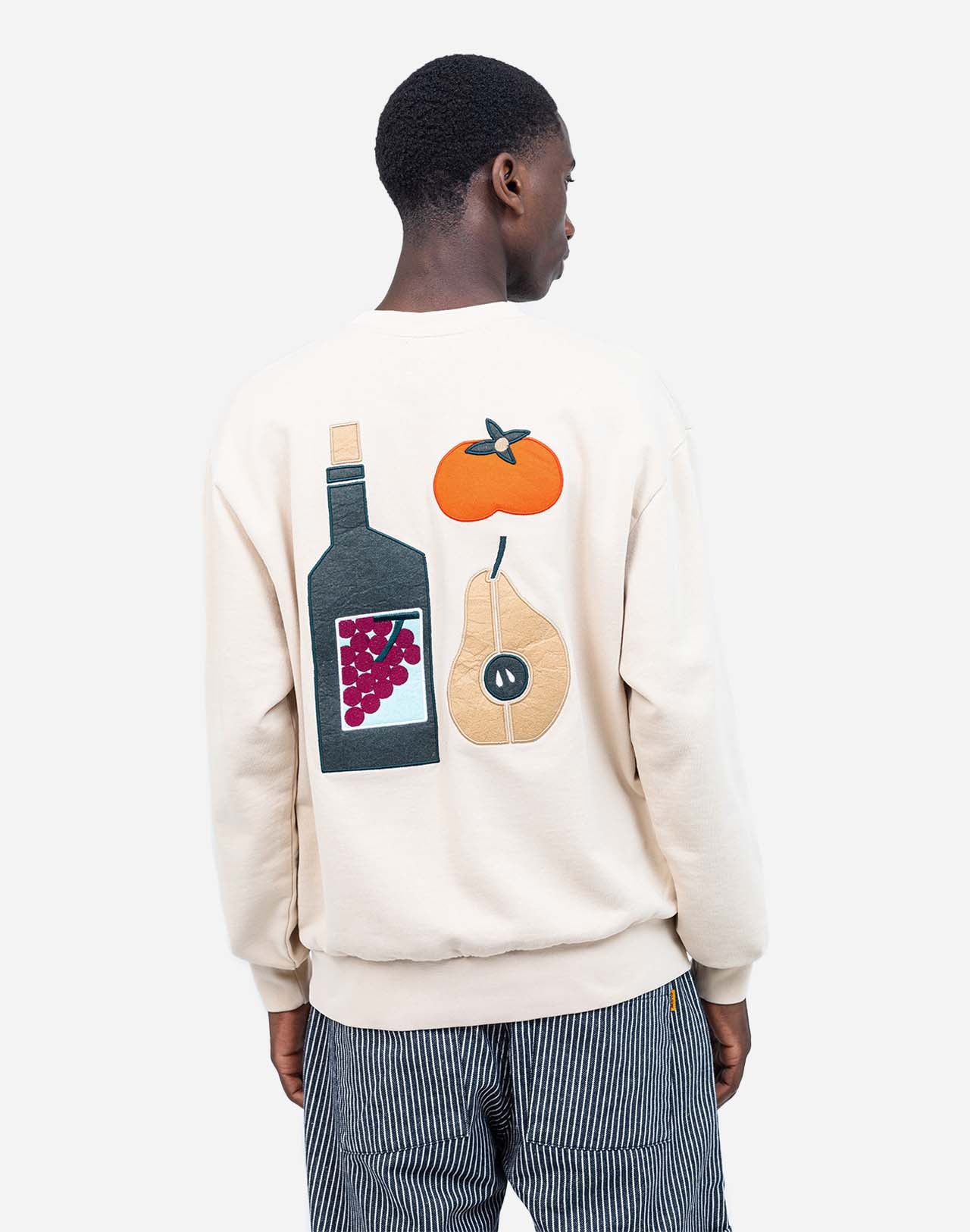 Loose-fit sweatshirt, crafted from GOTS-certified organic cotton fleece with a soft touch. Ribbed trims define the silhouette. At its heart, an embroidered patch, and on the back, felt inserts add depth to the illustration by artist Caìt McEniff.