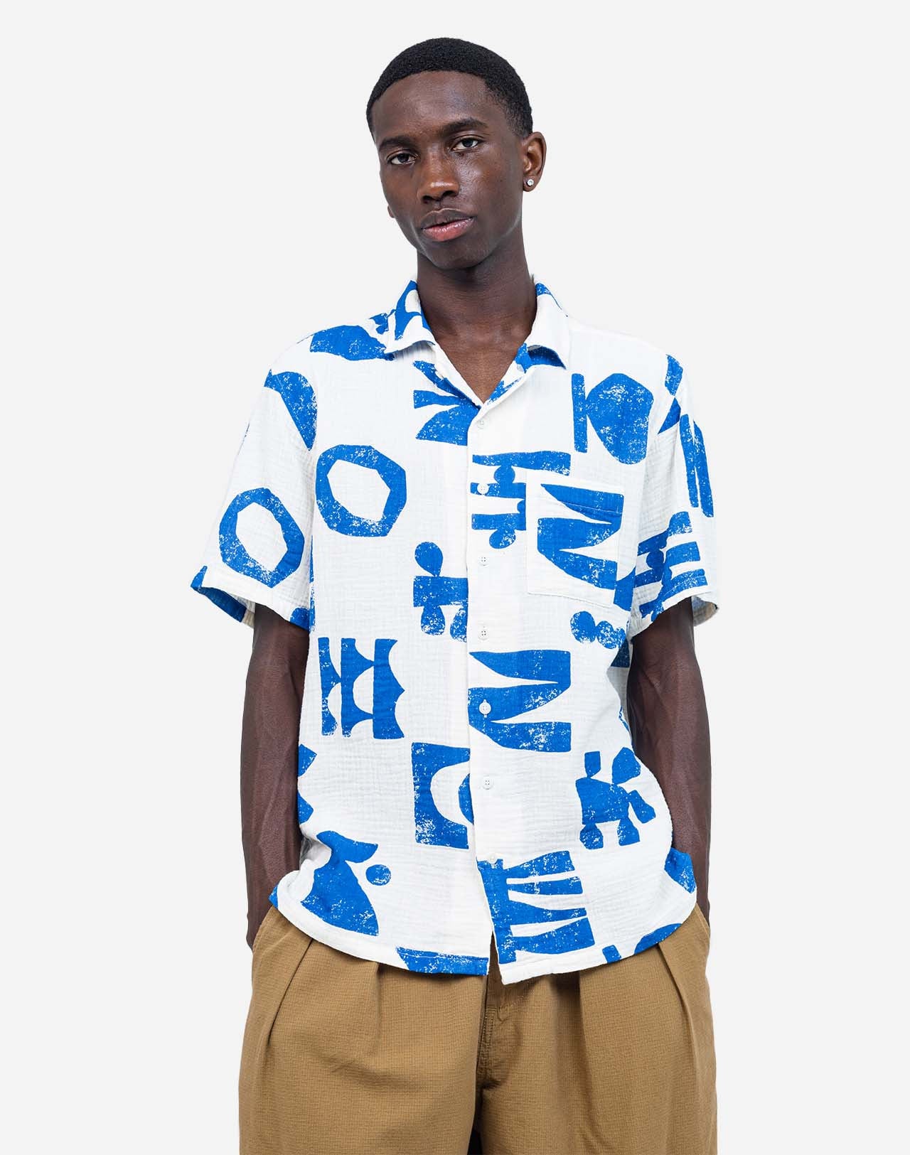 The graphic shapes imagined by artist Caìt McEniff adorn this Hawaiian-cut short-sleeved shirt in an all-over screen print. A summery, lightweight, and relaxed silhouette, defined by the contrast between bright white and intense blue. Crafted from 100% organic cotton gauze with corozo buttons, the Aloha Shapes shirt offers a breathable and easy-to-wear fabric. Its chest pocket and unique pattern make it a piece that is easy to pair.

