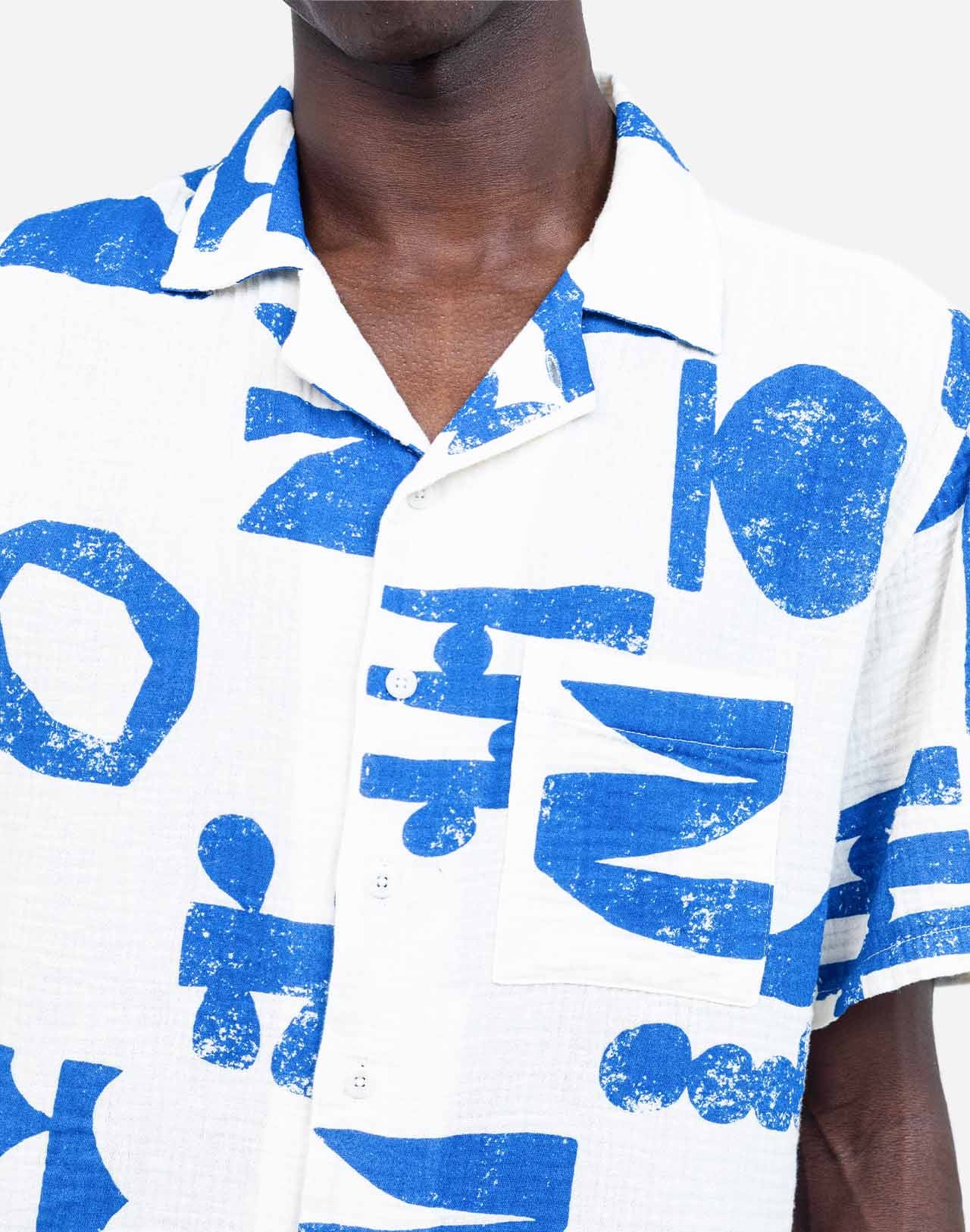 The graphic shapes imagined by artist Caìt McEniff adorn this Hawaiian-cut short-sleeved shirt in an all-over screen print. A summery, lightweight, and relaxed silhouette, defined by the contrast between bright white and intense blue. Crafted from 100% organic cotton gauze with corozo buttons, the Aloha Shapes shirt offers a breathable and easy-to-wear fabric. Its chest pocket and unique pattern make it a piece that is easy to pair.
