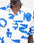 The graphic shapes imagined by artist Caìt McEniff adorn this Hawaiian-cut short-sleeved shirt in an all-over screen print. A summery, lightweight, and relaxed silhouette, defined by the contrast between bright white and intense blue. Crafted from 100% organic cotton gauze with corozo buttons, the Aloha Shapes shirt offers a breathable and easy-to-wear fabric. Its chest pocket and unique pattern make it a piece that is easy to pair.
